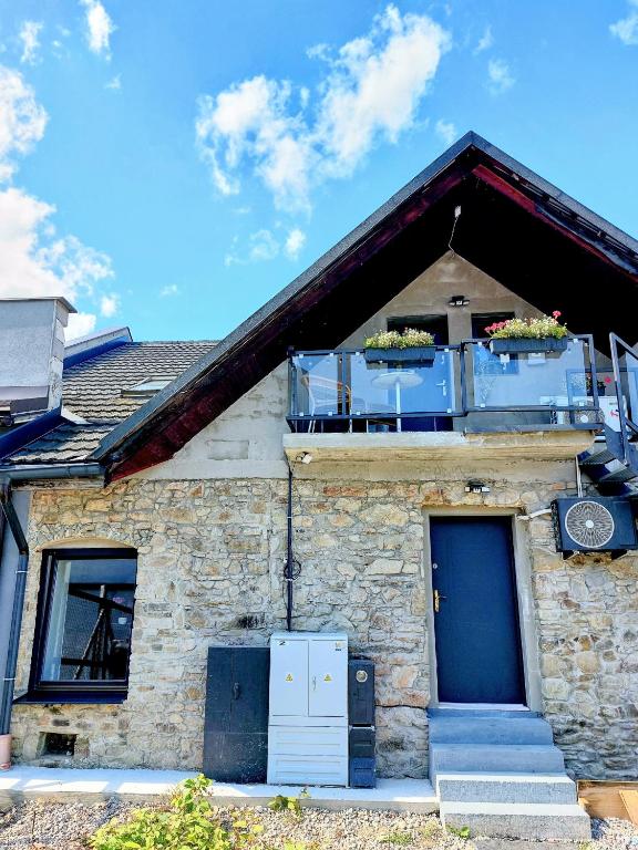 a stone house with a balcony and a blue door at Ubytovanie Čadca 2026 in Čadca