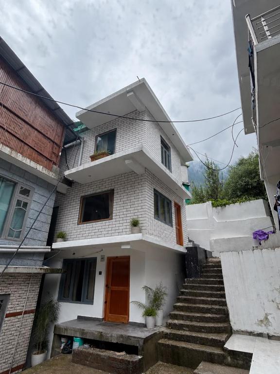 a white house with stairs in front of it at Man Mauji Villa in Kasol