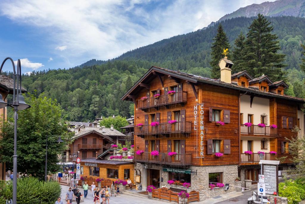 a building in the mountains with people walking around it at Hotel Courmayeur in Courmayeur