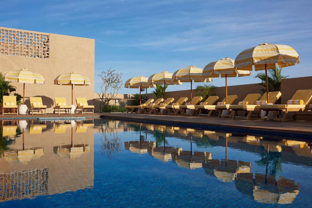a pool with chairs and umbrellas and a building at Kleo Seminyak, part of JdV by Hyatt in Seminyak
