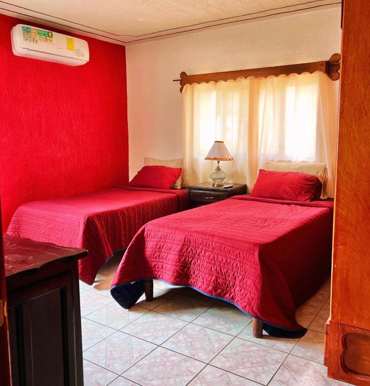 two beds in a room with red walls at La prieta linda in Tamasopo