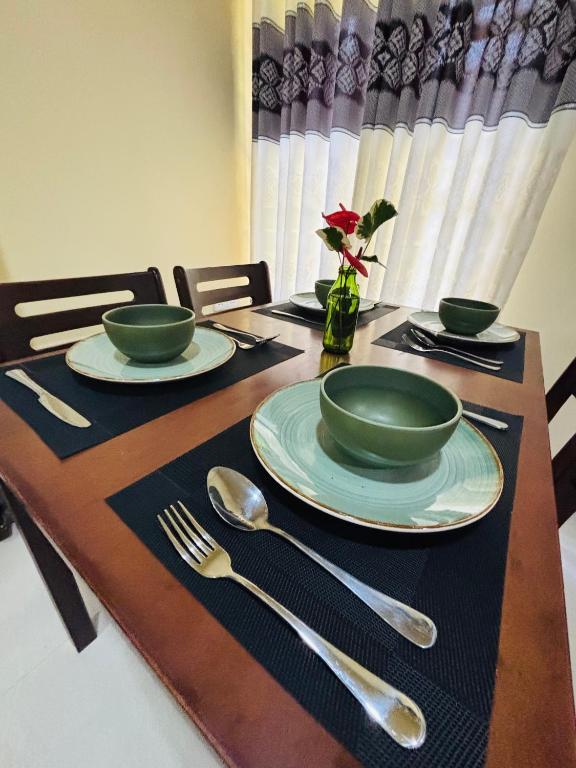 a wooden table with plates and silverware on it at Sun land Villa in Hikkaduwa