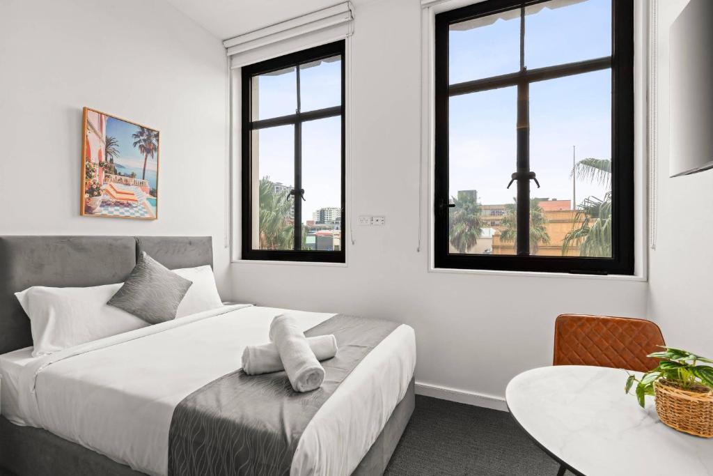 a bedroom with a bed and a table and windows at Comfort Inn Geelong in Geelong