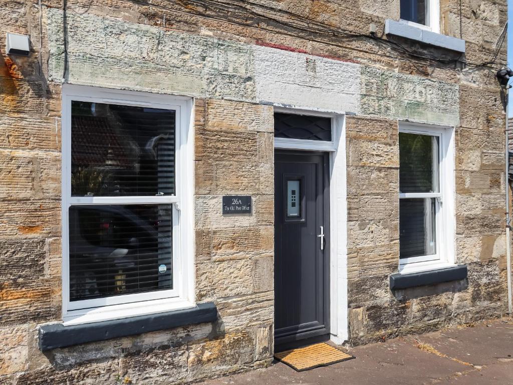 a brick building with a door and two windows at The Old Post Office in Kingskettle
