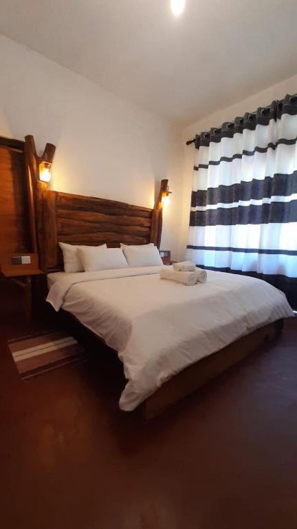 a bedroom with a large white bed with windows at Kadura Resort in Ella