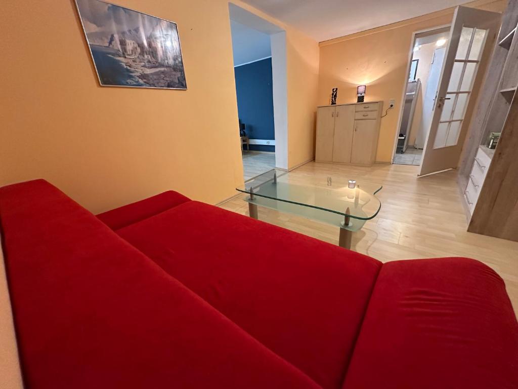 a living room with a red couch and a glass table at Souterrain Zimmer mit Sauna in Klosterlechfeld