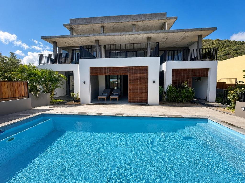 a villa with a swimming pool in front of a house at Sea Esta in Le Morne