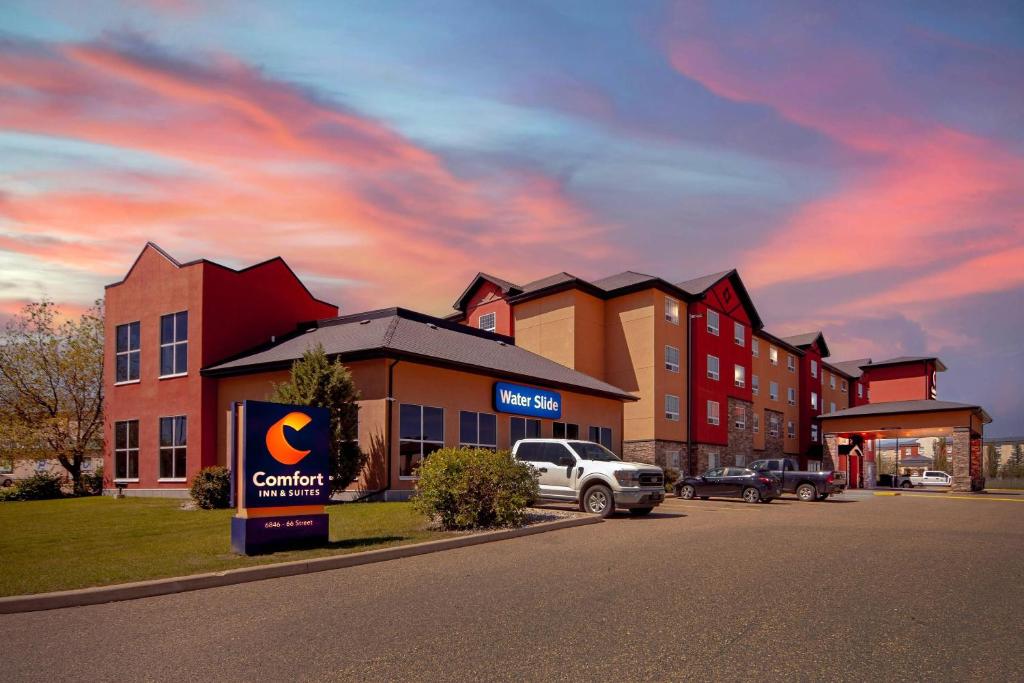 a building with a car dealership in a parking lot at Comfort Inn & Suites Red Deer - Highway 11 in Red Deer