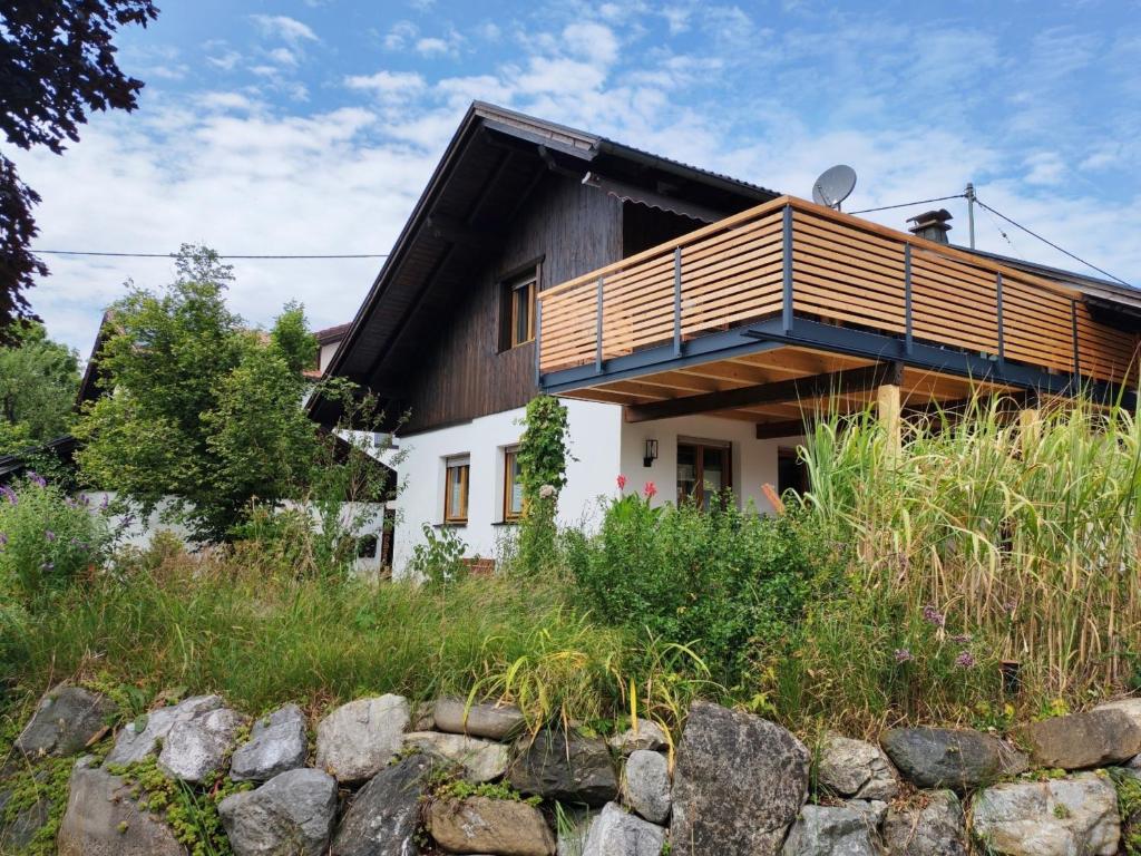 a house with a wooden roof and a stone wall at Ferienwohnung Mei Ruh' in Burggen