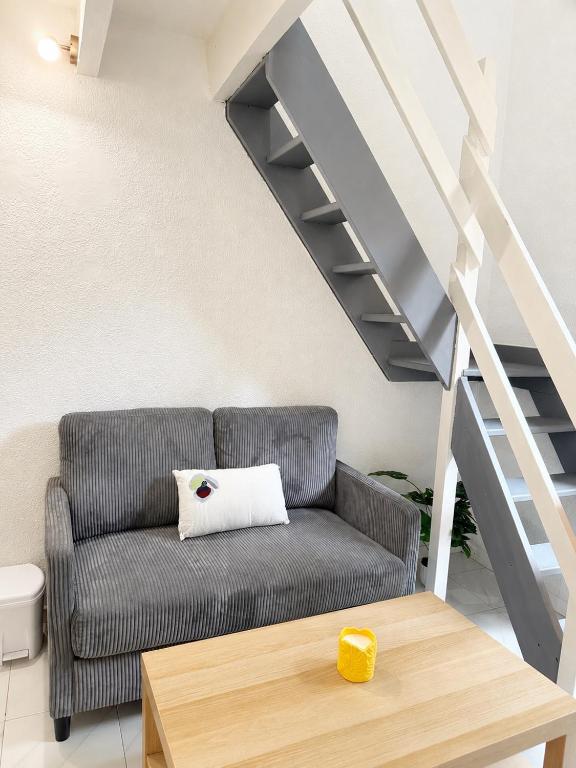a living room with a couch and stairs at Cosy T1 Bis climatisé in Toulouse