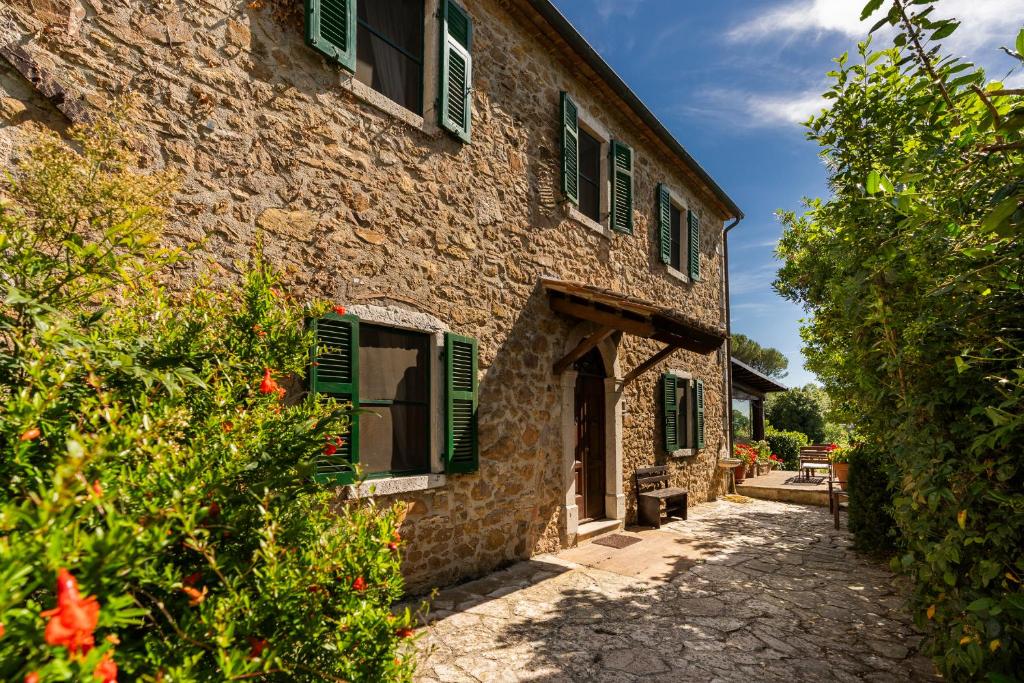 a stone building with green shutters on it at CASA LORY Poggio Murella in Poggio Murella