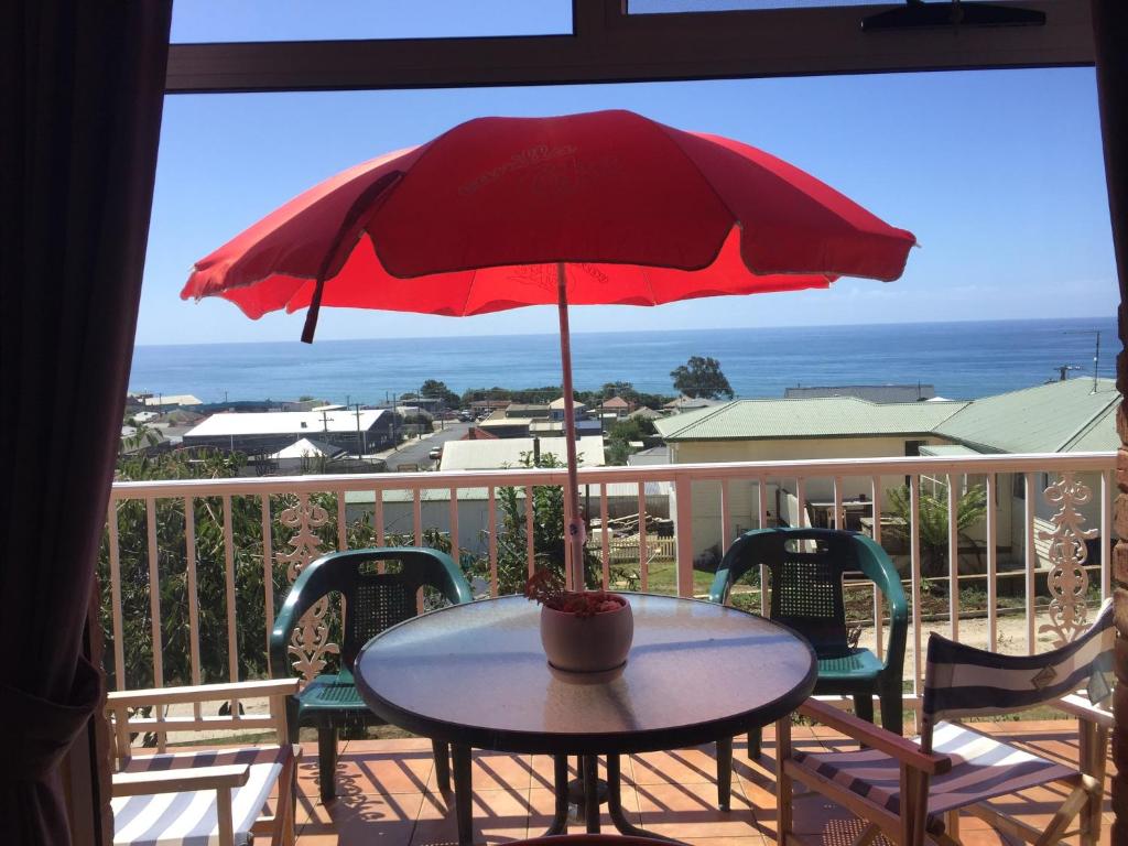 a table with a red umbrella on a balcony at Penguin Seaside Homestay in Penguin