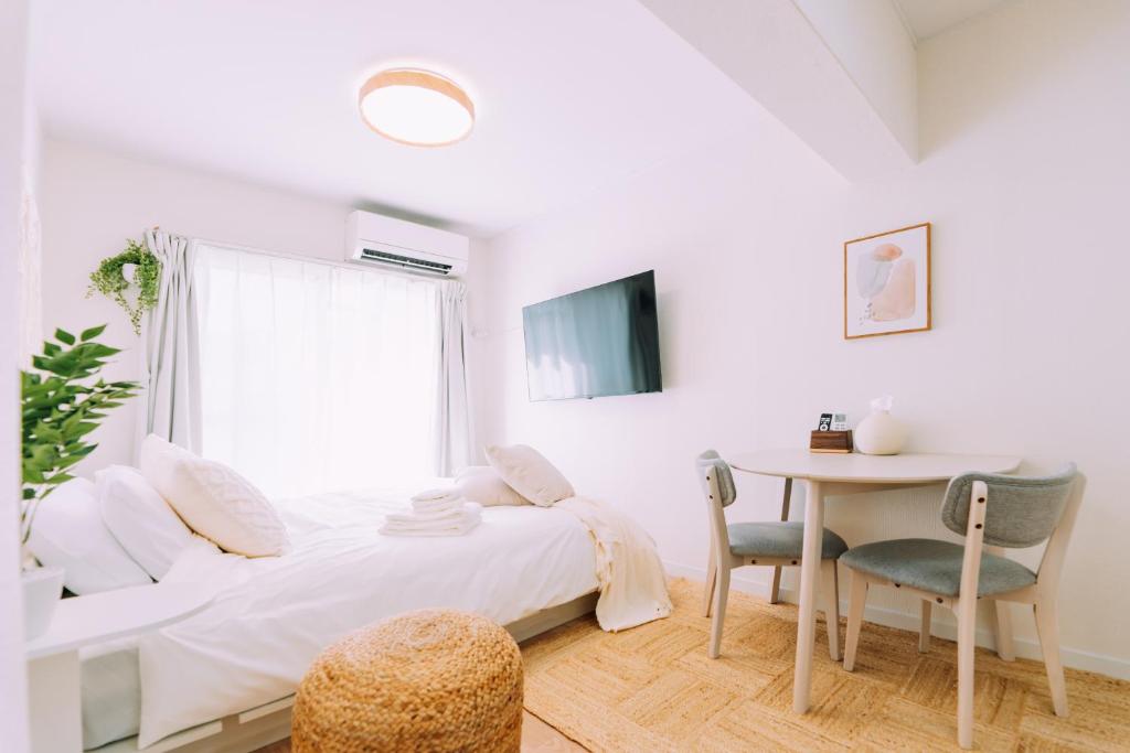 a white bedroom with a table and a bed at Chic 1 Bedroom Space Near Nakasu in Fukuoka