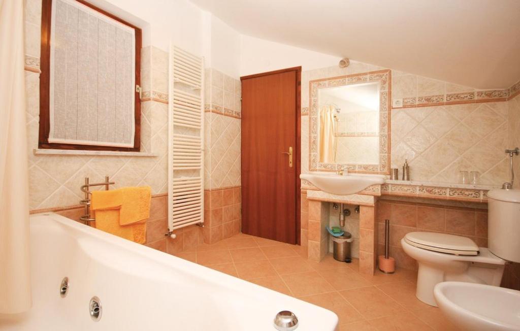 a bathroom with a tub and a toilet and a sink at Apartments villa MaVeRo in Banjole