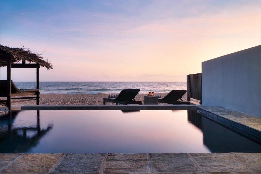 a swimming pool on the beach at sunset at Blue Parrot Beach Villa with privat swimming pool in Ambalangoda