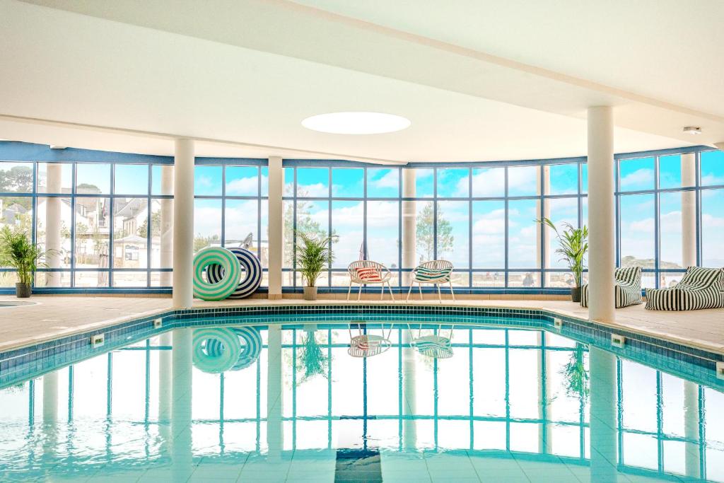 a swimming pool in a building with windows at Les Résidences d'Armor Ternélia Hôtel-Résidence in Douarnenez