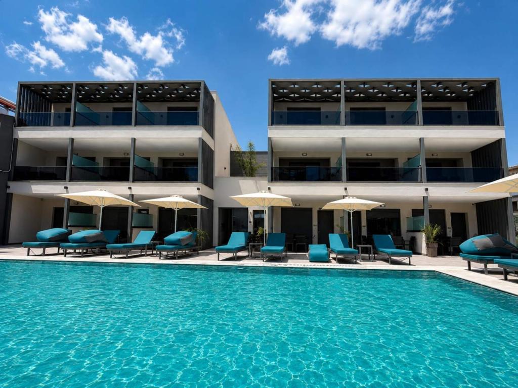 a hotel with a swimming pool and chairs and umbrellas at MARTINI APARTMENTs in Nikiti