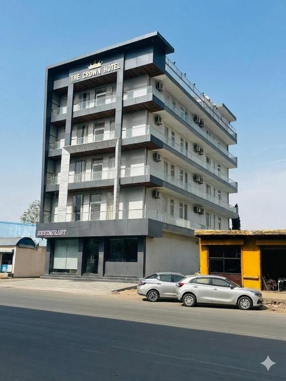 two cars parked in front of a large building at THE CROWN HOTEL & restaurants in Farrukhnagar