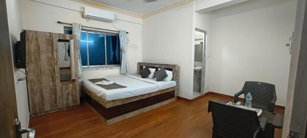 a bedroom with a bed and a desk and a window at M A P Hotel in Nager Bazaar