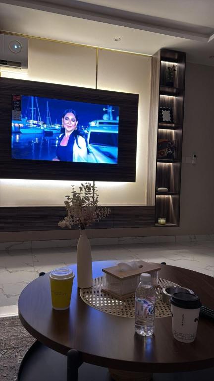 a living room with a table and a tv at شقة غرفتين وصالة مريحة in Jeddah