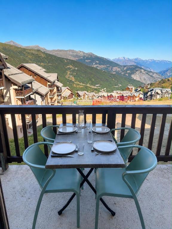 a table and chairs on a balcony with a view at Les balcons de Valmi vue montagne Piscine in Valmeinier