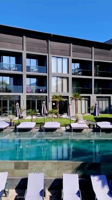 a pool in front of a building with chairs and umbrellas at Donau Resort in Eşelniţa
