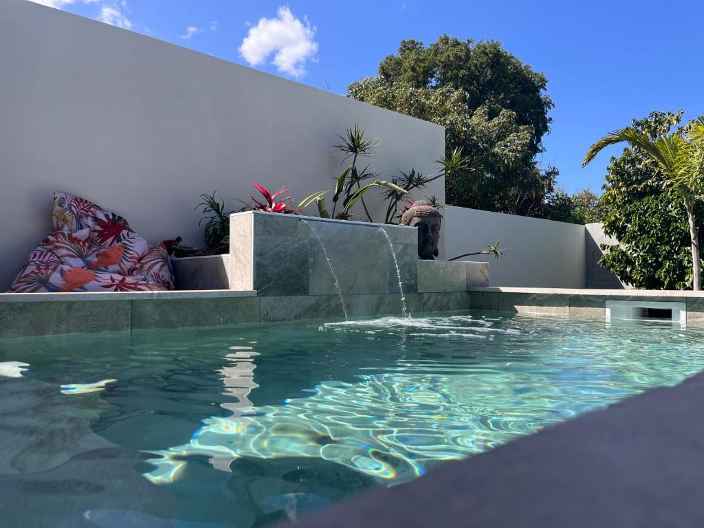 a swimming pool with a fountain in the middle at Case Ylang Blossom in Étang-Salé