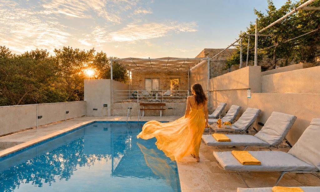 a woman in a dress standing next to a swimming pool at Cretan Breeze Villa Heated Pool in Dhrámia