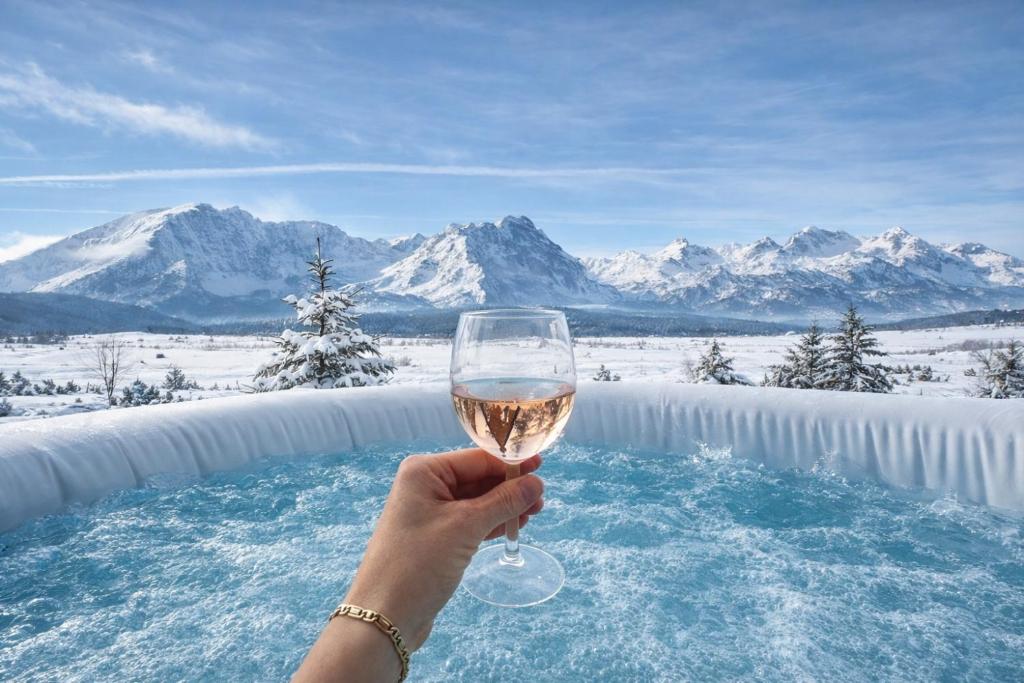 a person holding a glass of wine in front of a pool at Horizons by PeaksView Chalets in Žabljak