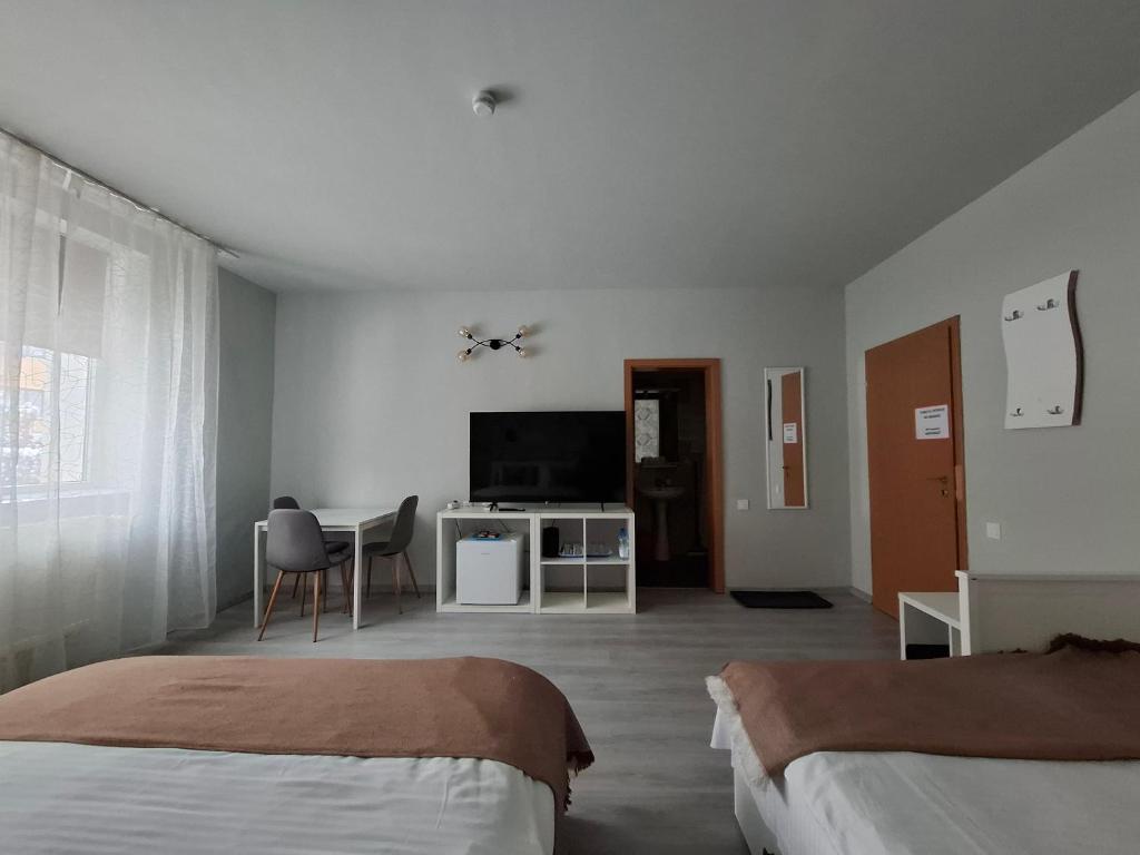 a bedroom with two beds and a table and a television at Pensiunea Paloma 3 stele Brasov in Braşov