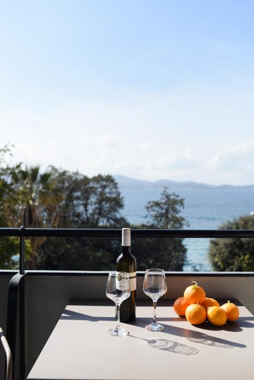 a table with two glasses of wine and oranges on it at Jelena - Spacious Sea View Apartment - Old Town Zadar in Zadar