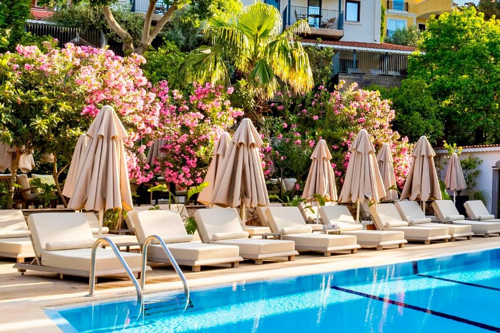 a row of chairs and umbrellas next to a swimming pool at True Blue Boutique Hotel Kalkan in Kalkan
