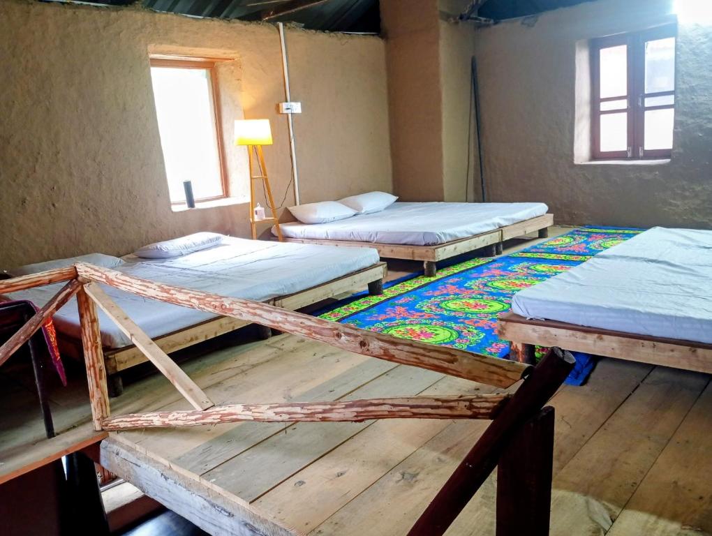 a room with three beds and a rug at DnD cottages in Mandi