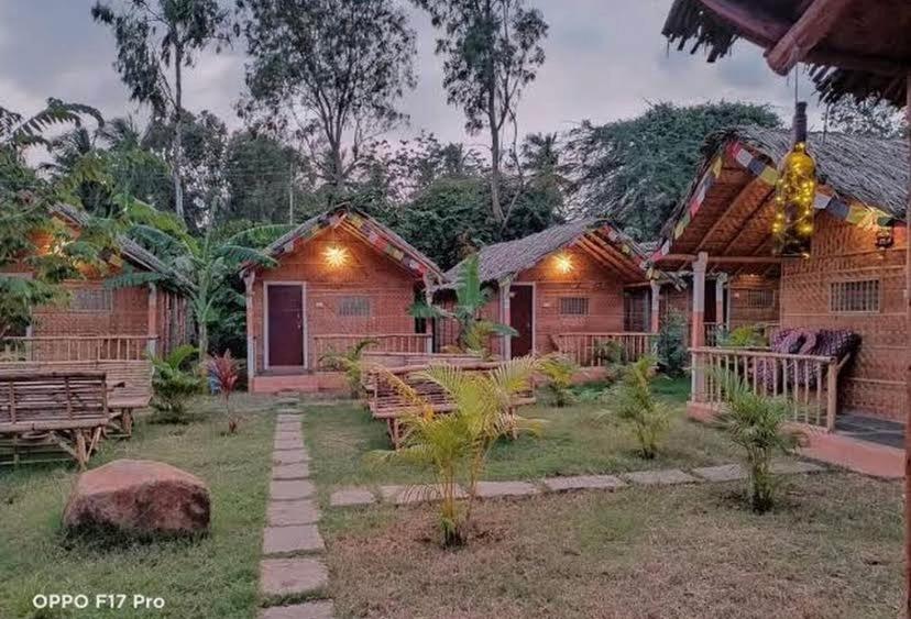 a resort with benches and tables in a yard at Sunshine café Hampi in Hampi