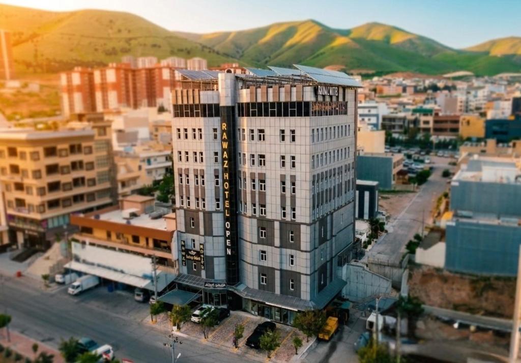 a tall white building on a city street with mountains at Rawaz Hotel in As Sulaymānīyah