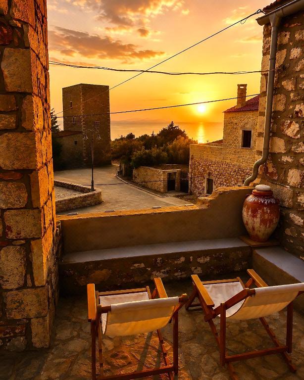 two chairs and a vase on a balcony with a sunset at Diaks Tower Sunset Sea View Mani in Pyrgos Dirou