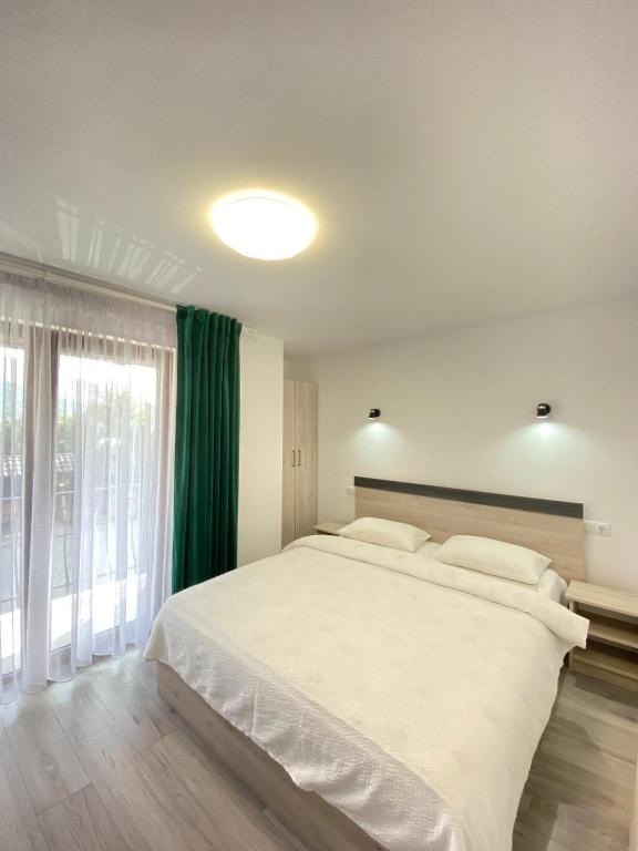 a bedroom with a large white bed and a large window at Pensiunea CARMEN Borșa in Borşa
