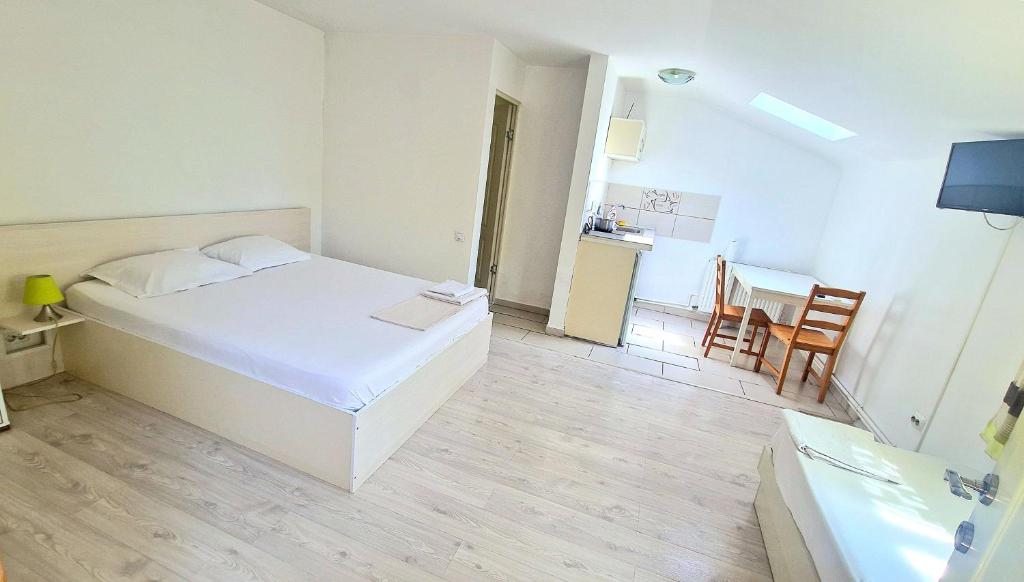 a white bedroom with a bed and a table at Titulescu Apartments in Bucharest