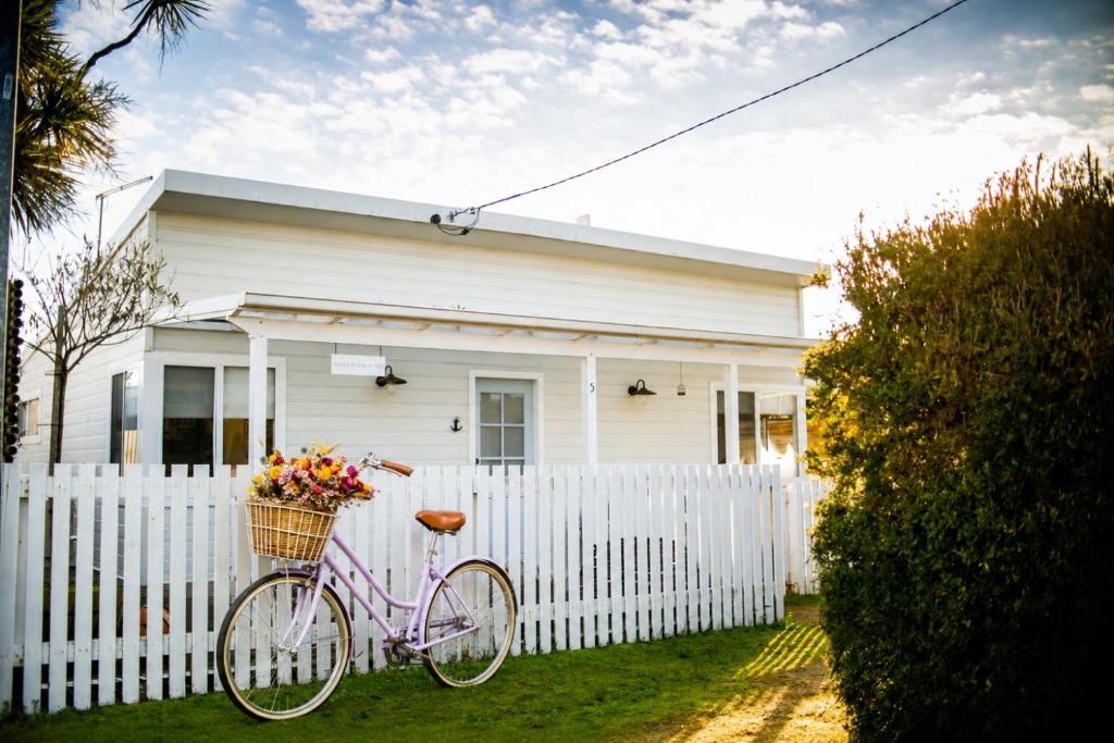 a pink bike parked in front of a white fence at Shack In The Dunes in Weymouth