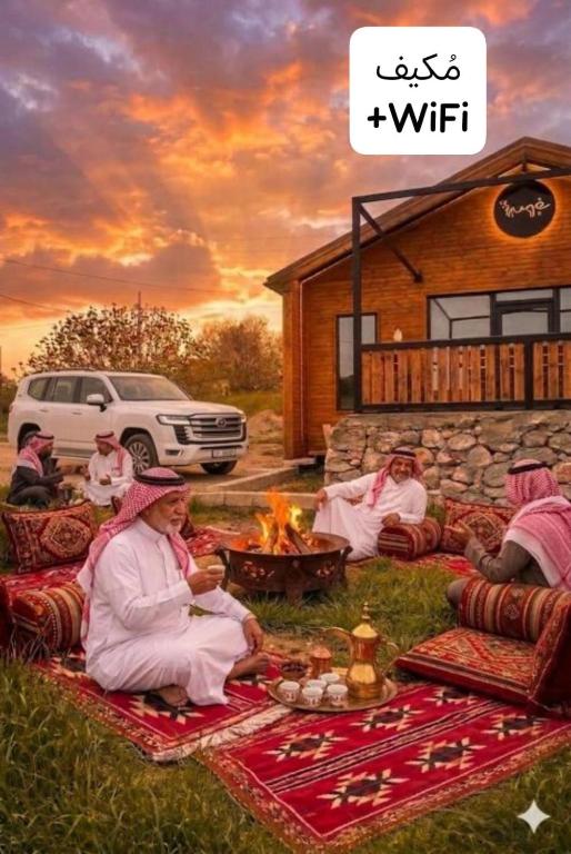 a group of people sitting around a fire in the grass at شاليه غصن in Ajloun