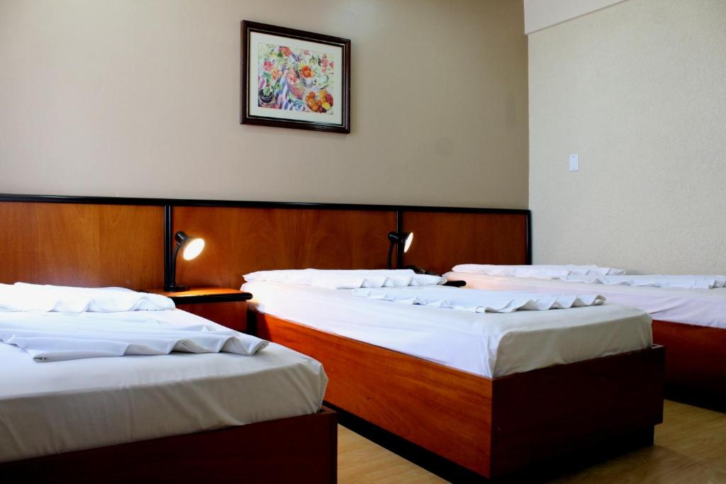 a group of three beds in a room at Geneviee Palace Hotel in Ponta Grossa