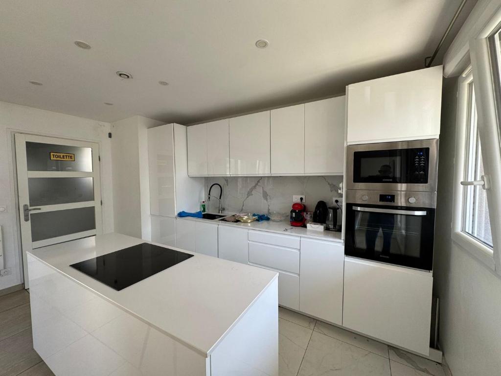 a kitchen with white cabinets and a white counter top at Emmanuel INN 4 in Drancy