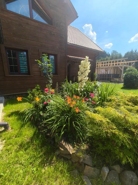 a garden in front of a house with flowers at Domek MAGELLAN Cisna 11 in Cisna