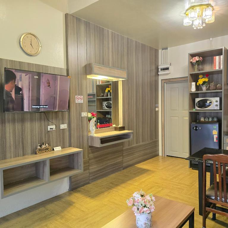 a living room with a table and a clock on the wall at Victory Place in Bangkok