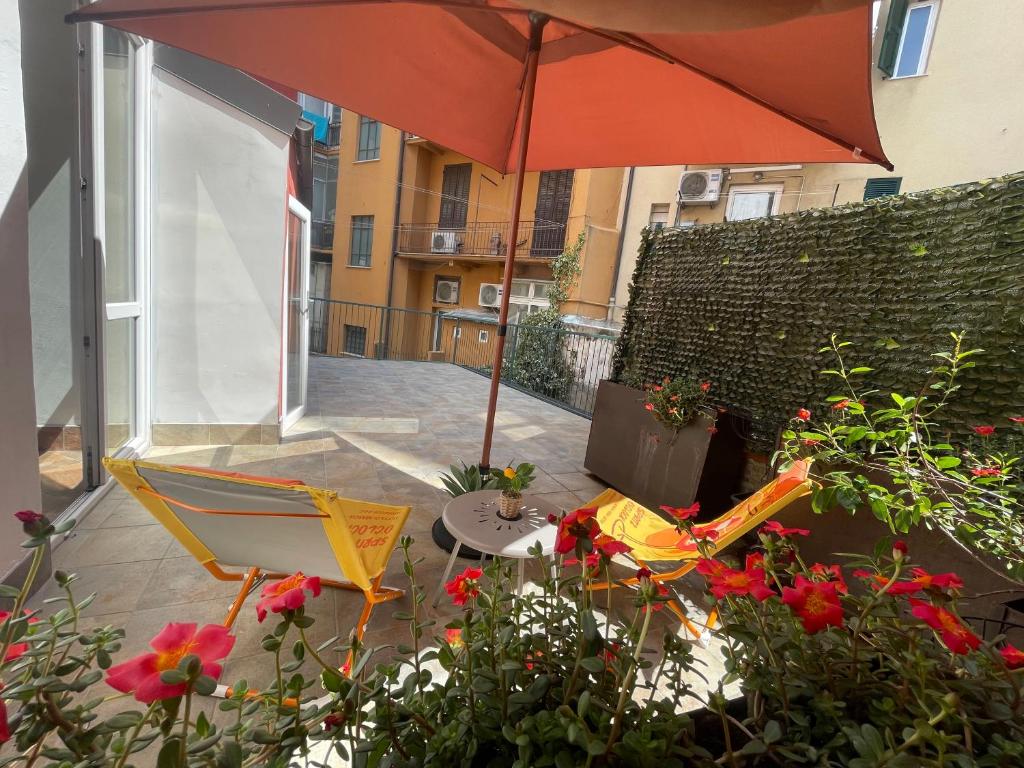 a patio with a table and an umbrella and flowers at Priamar house in Savona