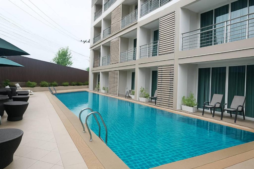 a swimming pool in front of a building at Retreat Resort Pattaya in Nong Prue