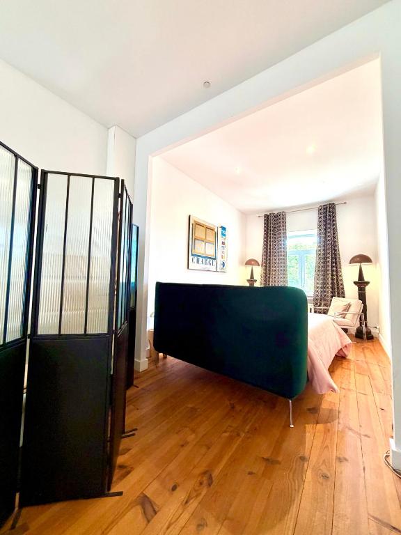 a living room with a bed and a room with wooden floors at Maison VCB Ciney - Hôtel Particulier de 1820, Cœur de Ville, Parc & Parking Privé in Ciney