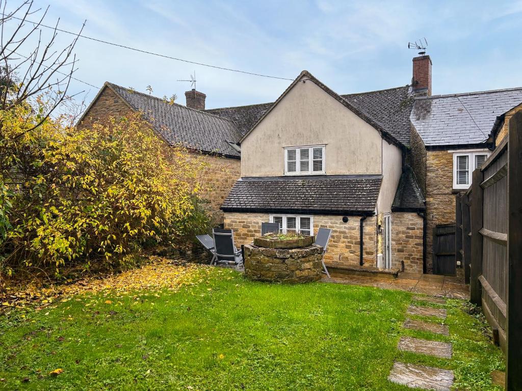 a house with two chairs in the yard at Hailey Cottage in Chipping Norton