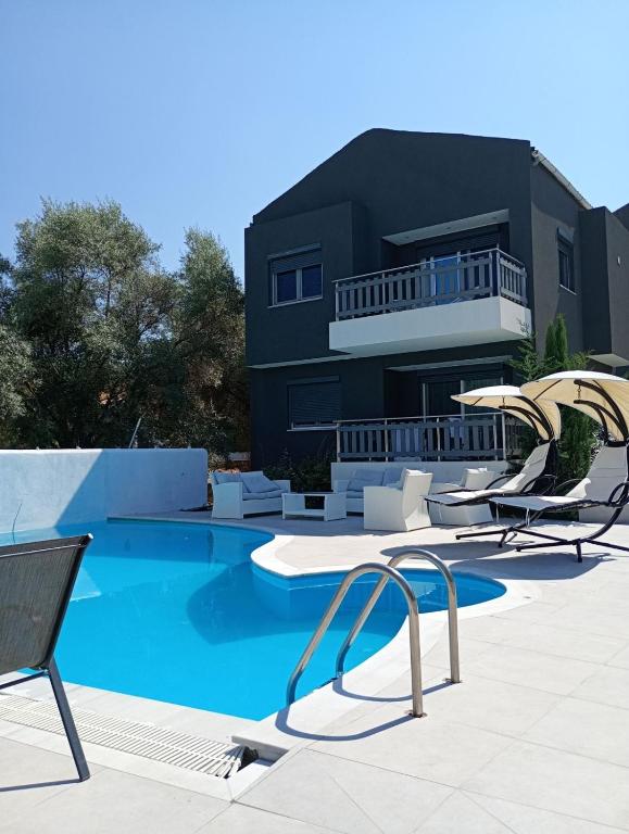a villa with a swimming pool with chairs and a house at Alivka Apartments in Apolpaina