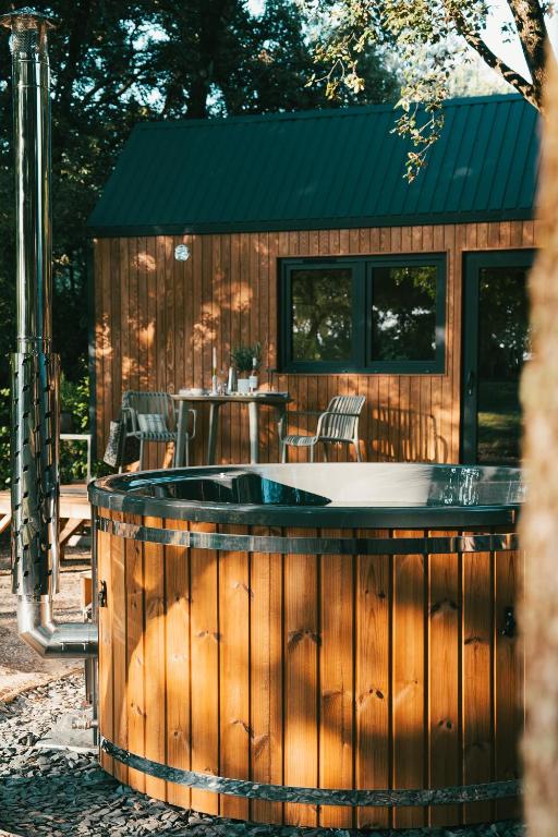 a large hot tub in front of a wooden building at La Tiny sous les pins in Noves